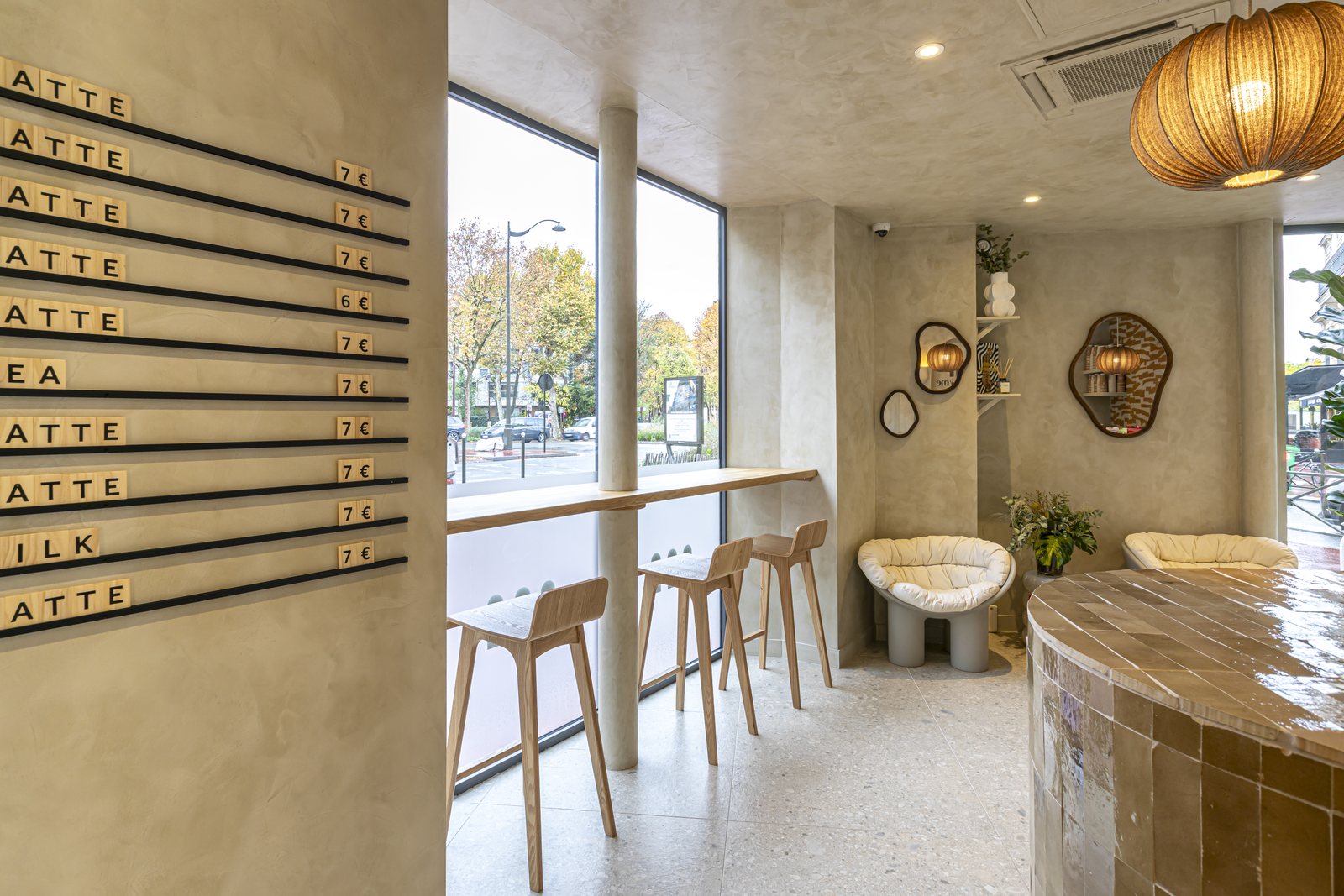 Le café : menu en lettres de bois sur réglettes noires, bar de chêne en vitrine, fauteuil et suspension en rotin