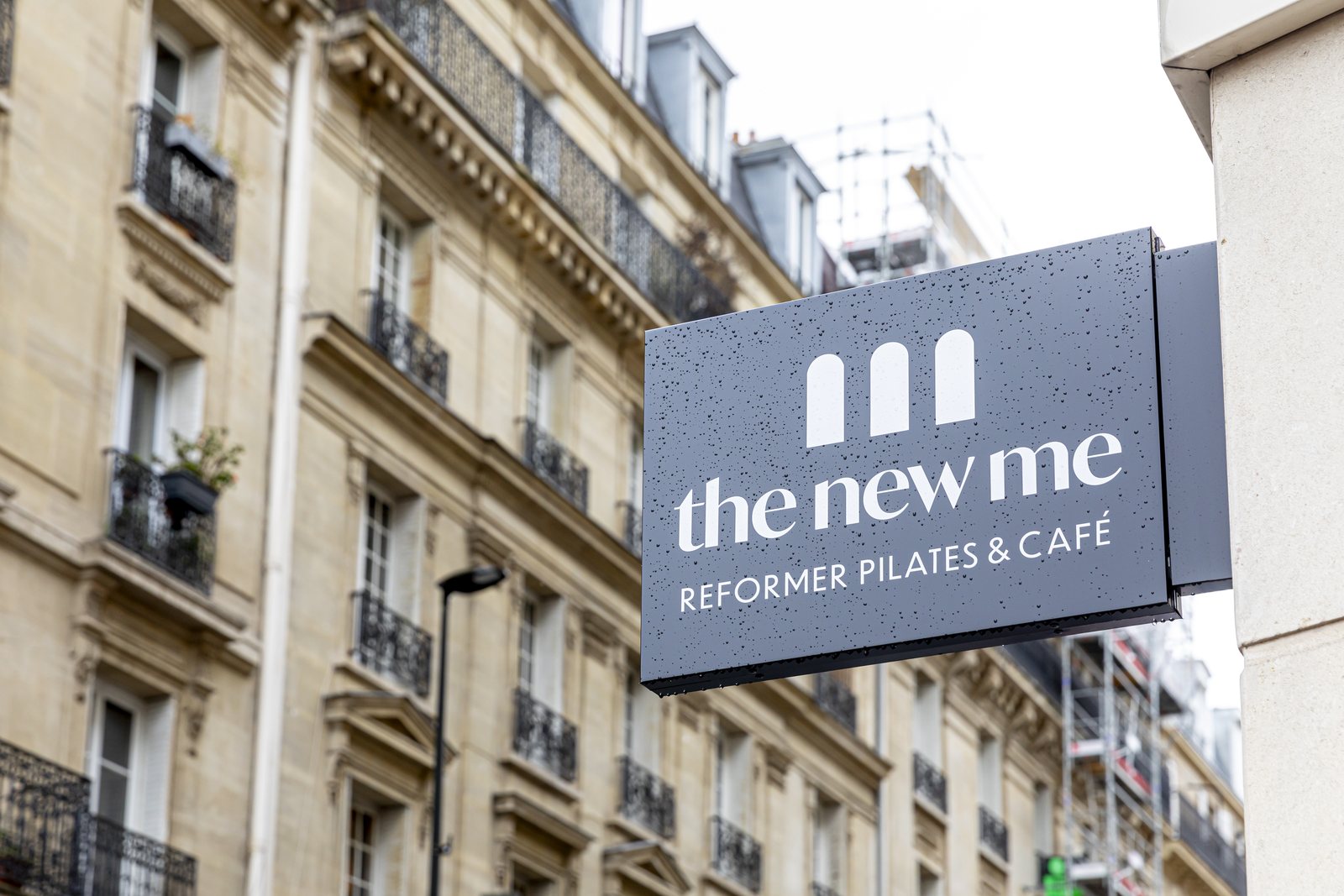 L'enseigne the new me — reformer pilates & café, trois arches, sur une façade haussmannienne
